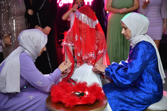 Eine Braut unter rotem Schleier bei ihrer Henna-Zeremonie